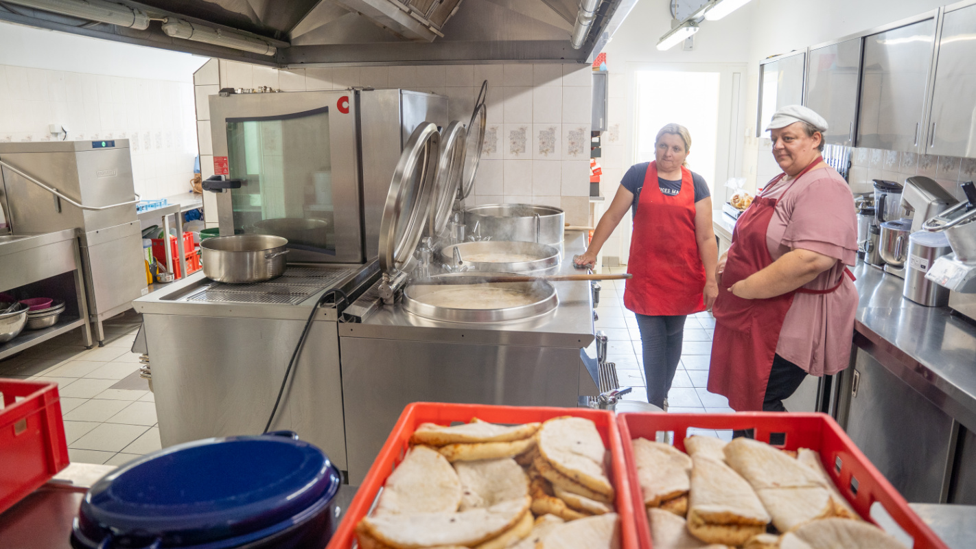 Armenküche, zwei Frauen arbeiten in einer Suppenküche, Pizza liegt auf dem Tisch, Balkan, Junge Leute Helfen, Arme, Hilfe, Not